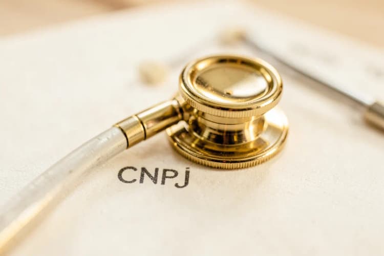 Um close-up de um estetoscópio dourado sobre um documento com carimbo de CNPJ.